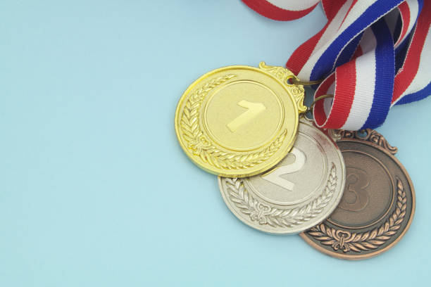 Gold, silver and bronze medal with ribbons on blue background close-up.