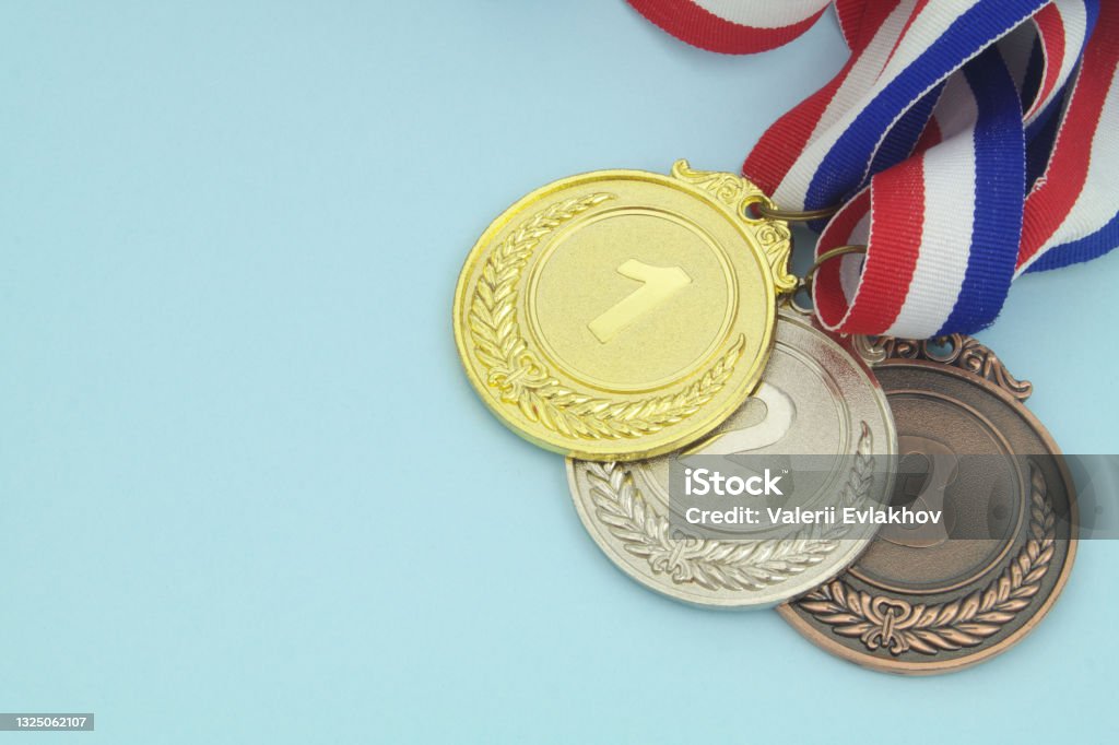 Gold, silver and bronze medal on blue background Gold, silver and bronze medal with ribbons on blue background close-up. Bronze Medal Stock Photo