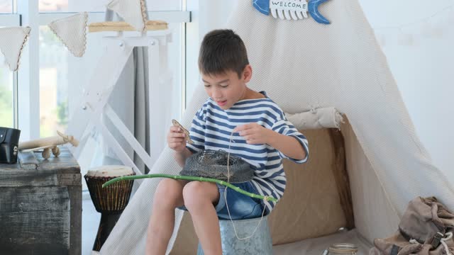 Little boy fishing with cage at home