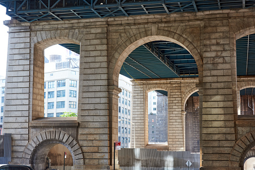 Brooklyn, NY - May 25, 2021: The granite structural support piers of the Manhattan Bridge on Pearl St in the Dumbo neighborhood of Brooklyn, NYC. The piers have a classical motif of rusticated columns and arches.