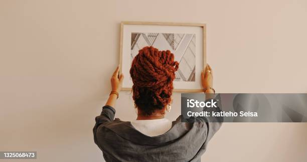 Shot Of A Unrecognizable Female Hanging A Painting At Home Stock Photo - Download Image Now