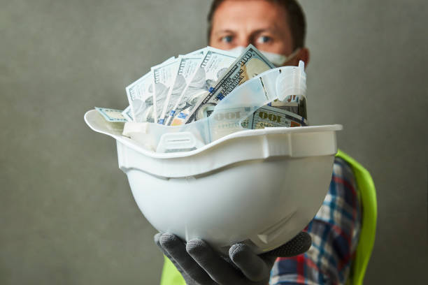 istock Construction worker with a hard hat full of dollar money 1325068549