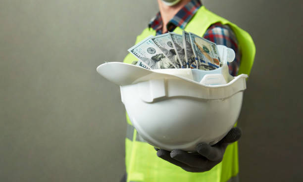 Construction worker with a hard hat full of dollar money