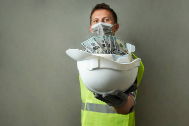 istock Construction worker with a hard hat full of dollar money 1325068561