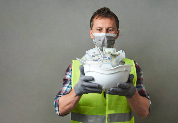 istock Construction worker with a hard hat full of dollar money 1325068589