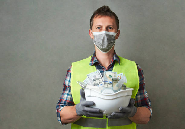 istock Construction worker with a hard hat full of dollar money 1325068591