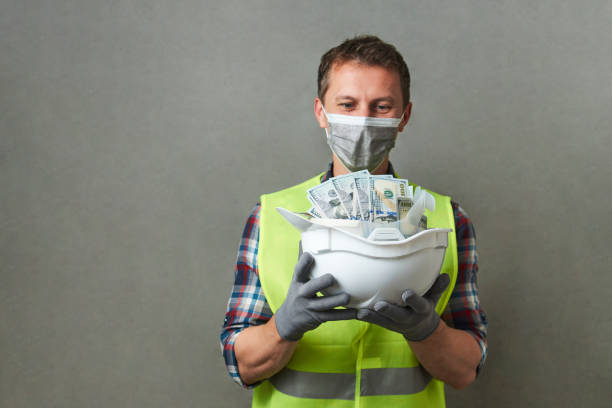 istock Construction worker with a hard hat full of dollar money 1325068594