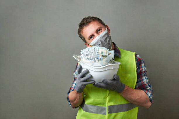 istock Construction worker with a hard hat full of dollar money 1325068600