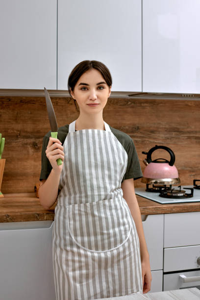 istock Young beautiful housewife holding knife on kitchen 1325070026