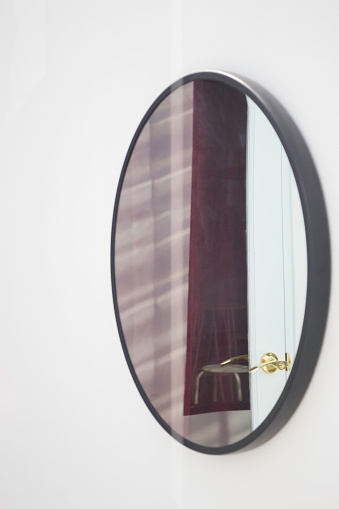 Black framed mirror on a white wall, stock photo