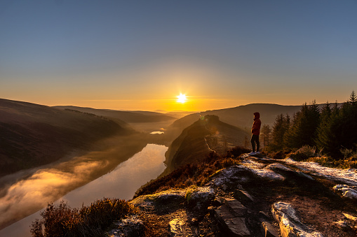 Man in orange jacket standing on the Spink Viewing Spot admiring the sunrise in Wicklow Ireland