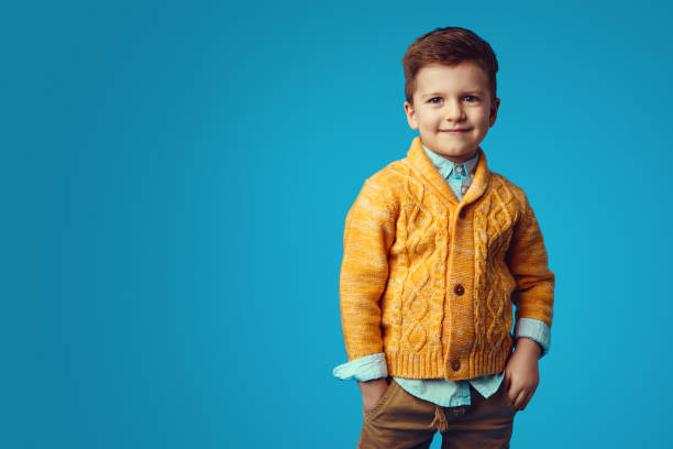 istock Boy smiling while holding hands in pockets, isolated over blue background 1325074404
