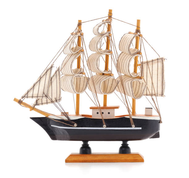 Toy boat sailboat on a wooden stand isolated on a black background. Model of the ship with a red stripe. side view