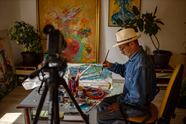 istock Focused artists making a video for his art channel using a tripod-mounted camera 1325076877