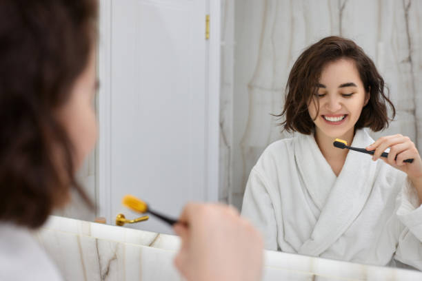 istock woman in white bathrobes brushing teeth in front of mirror 1325080531
