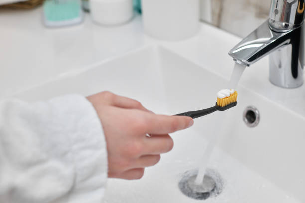 istock female hand holding toothbrush with paste in bathroom 1325080602