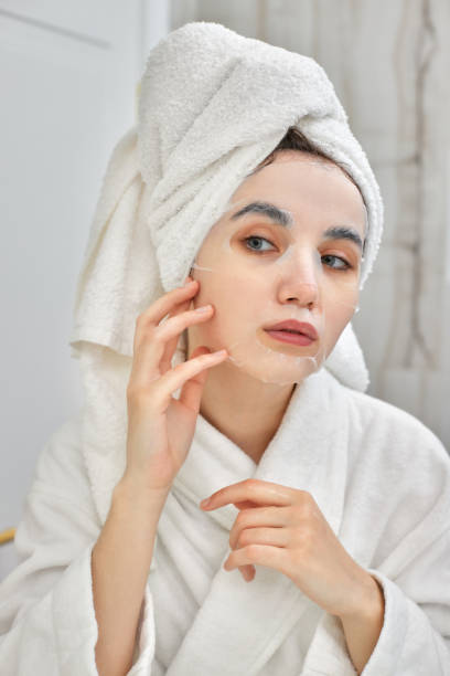 istock woman in white bathrobe in front of mirror in bathroom 1325081966