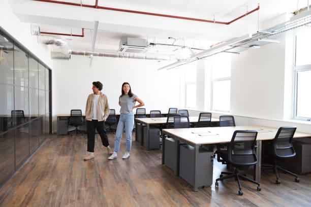 istock Young couple looking at work space for start up business to rent walking into empty open plan office 1325083806