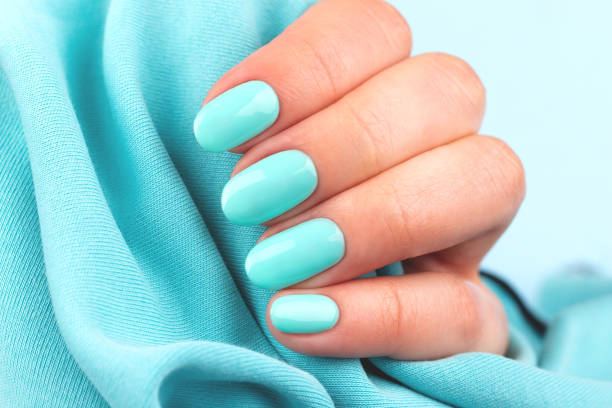 istock Hand with turquoise nails on blue textile background 1325086863
