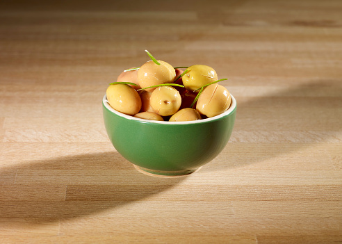 Green olives in the bowl on wooden table