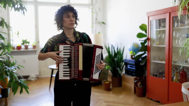 Non-binary person playing accordion at home