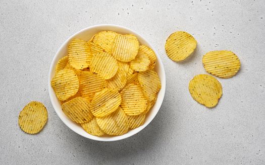 Ridged potato chips in bowl with copy space, top view