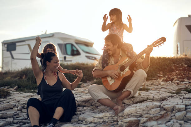 familia de vacaciones, cantando, tocando música con una guitarra y disfrutando de las vibraciones de verano. - rv fotografías e imágenes de stock