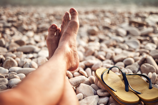 Man sunbathing on a rocky sea ocean beach.