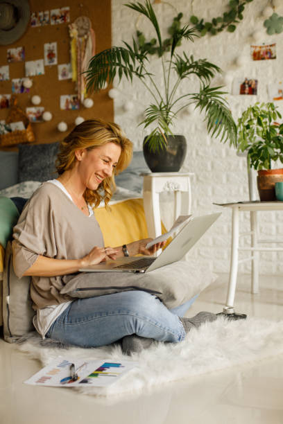 istock Cheerful woman working from home, using laptop and reviewing documents 1325093719