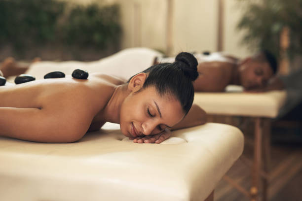 strzał młodej kobiety coraz masaż gorącymi kamieniami w spa - pampering massaging indoors adult zdjęcia i obrazy z banku zdjęć