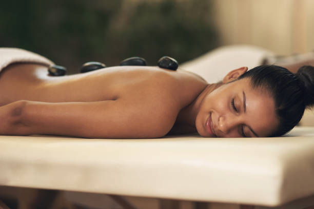 foto de una joven recibiendo un masaje con piedras calientes en un spa - massage stones fotografías e imágenes de stock