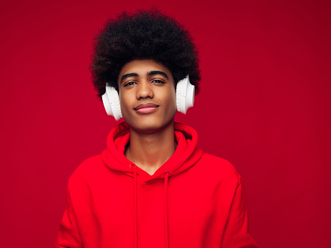 African american man with african hairstyle wearing hoodie standing over isolated red background