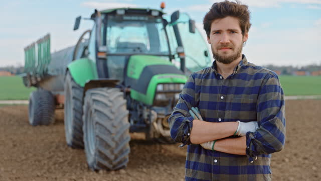 Young farmer standing with arms crossed on field