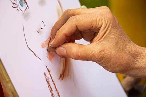 Artista callejero dibujando retrato de chicas cómicas. Fotografía de cerca de manos y suministros de dibujo. Dibujaba detrás del caballete con papel blanco. photo