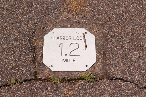 A close view of the metal trail distance sign on the walk.