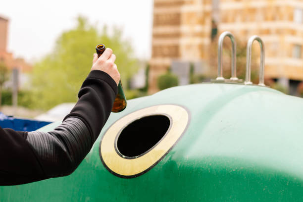 la mano de un hombre reciclando una botella de vidrio en un recipiente. concepto de reciclaje y cuidado del medio ambiente - recycling recycling symbol environmentalist people fotografías e imágenes de stock