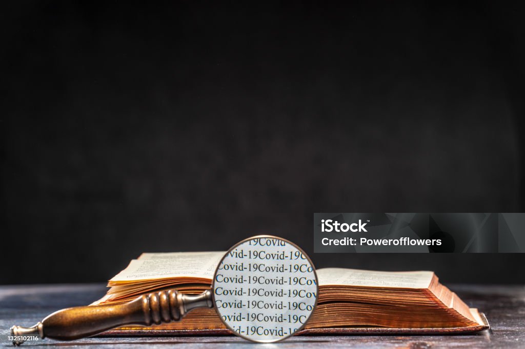 The words of Ð¡ovid 19 are read through the magnifying glass lying on the table next to the book. Coronavirus Knowledge Concept The words of Ð¡ovid 19 are read through the magnifying glass lying on the table next to the book. Coronavirus Knowledge Concept. COVID-19 Stock Photo