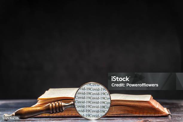 The Words Of Ðovid 19 Are Read Through The Magnifying Glass Lying On The Table Next To The Book Coronavirus Knowledge Concept Stock Photo - Download Image Now