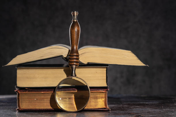 istock A stack of old books lying on a table on a dark background and magnifying glass 1325102144
