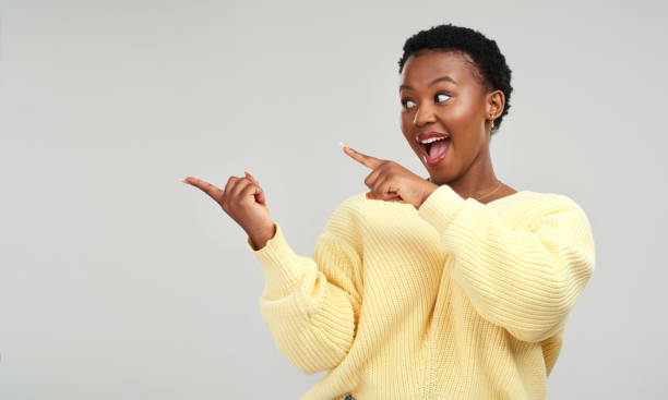 istock Shot of a young woman pointing at copy-space while posing against a grey background 1325102499
