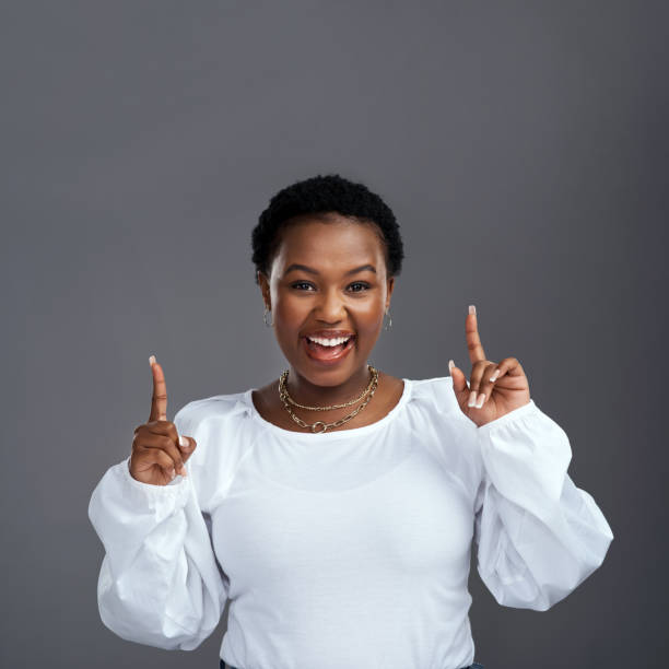 istock Shot of a young woman pointing at copy-space while posing against a grey background 1325102520