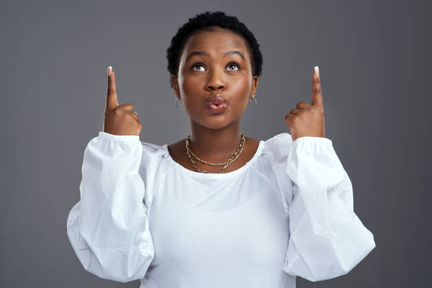 istock Shot of a young woman pointing at copy-space while posing against a grey background 1325102575