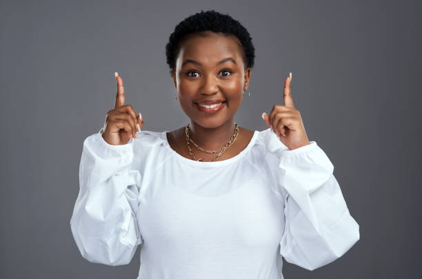 istock Shot of a young woman pointing at copy-space while posing against a grey background 1325102581
