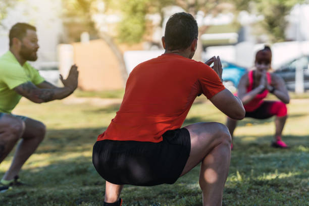 istock Group of people doing squats outdoors 1325102776