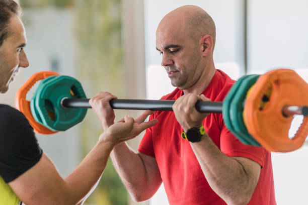istock Man lifting weights with the help of a coach 1325103647