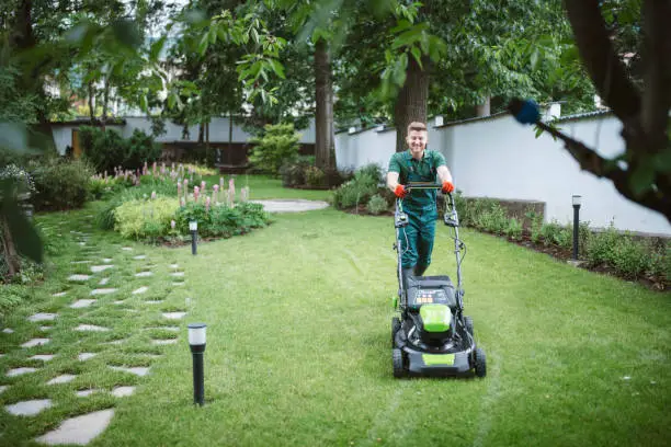 Photo of Gardener Mows The Lawn With An Mower.