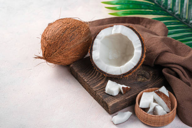 istock Ripe coconut on a light pink background with a palm branch. Tropical fruit 1325111853