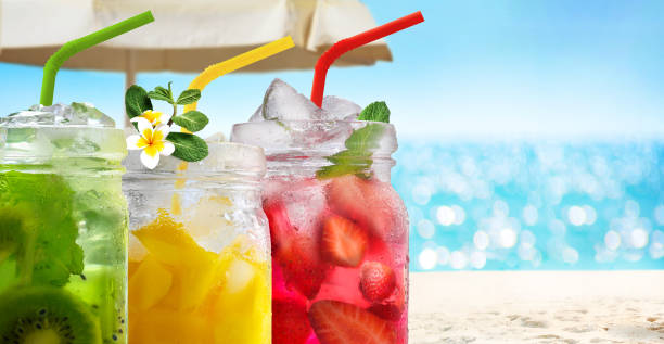 Summer refreshing exotic drinks cocktails in glass jars with straws on seascape with bokeh sun light background. Summer refreshing exotic drinks cocktails in glass jars with straws on seascape and sand beach background. beach umbrella photos stock pictures, royalty-free photos & images