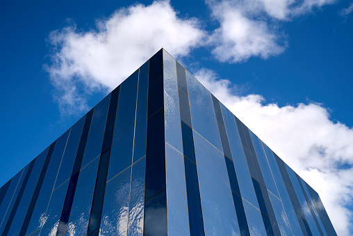 Angle glass modern office building detail, blue white cloudy sky