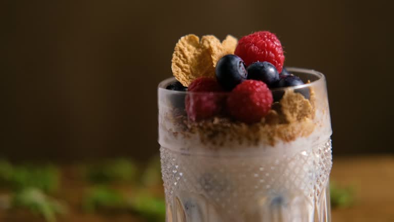 Close up on granola with yogurt and berries for healthy breakfast on a wooden table. Dark style photography.